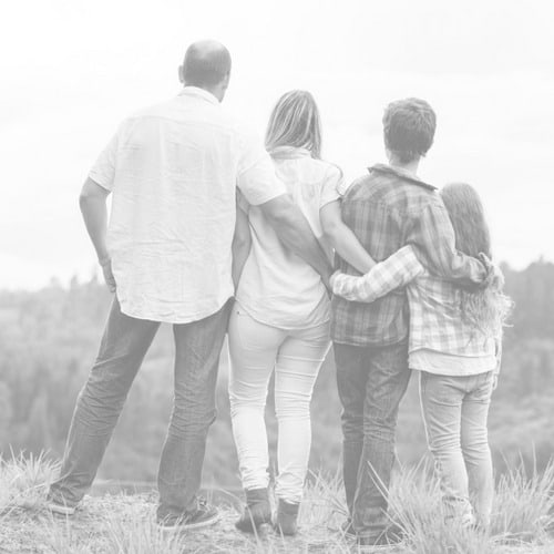 a family of four with their backs to the camera looking out over a mountain