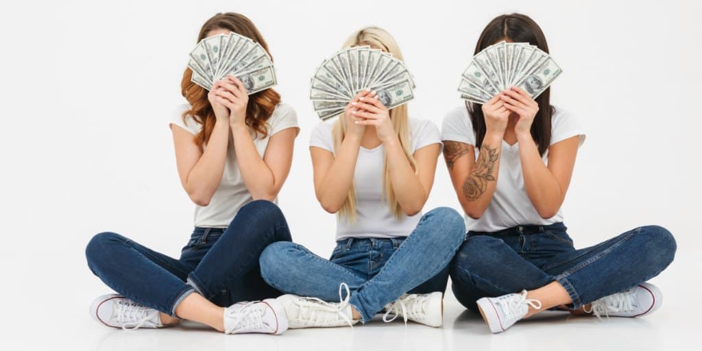 3 vrouwelijke tieners wuiven cash geld voor hun gezicht