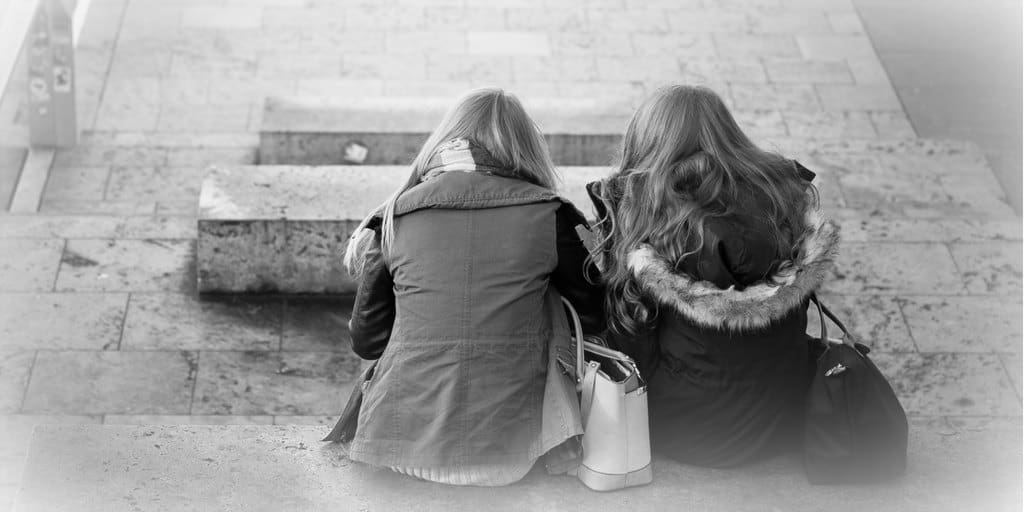 two sisters sitting outside side by side