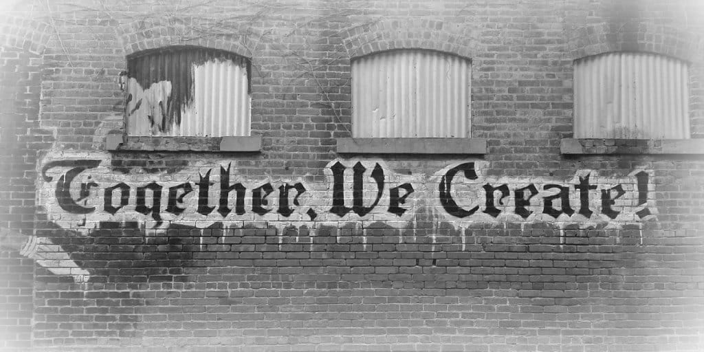 side of brick building with the words together we create painted on it