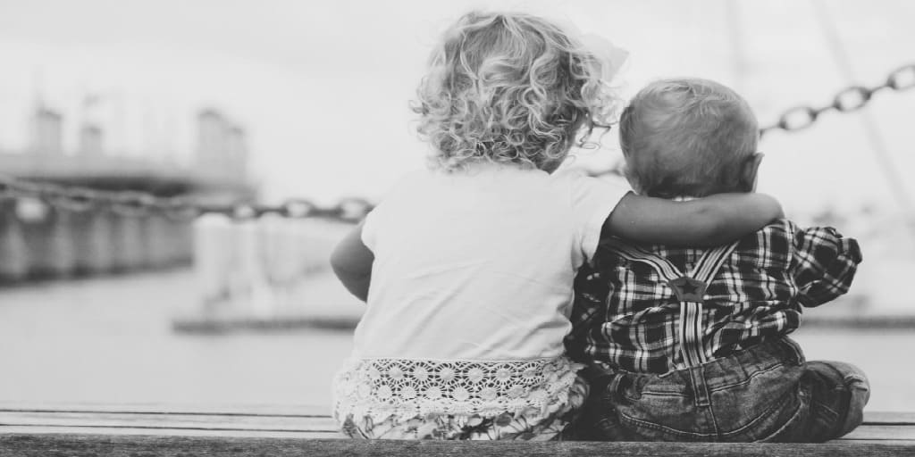 two small children looking at sail boats on the water