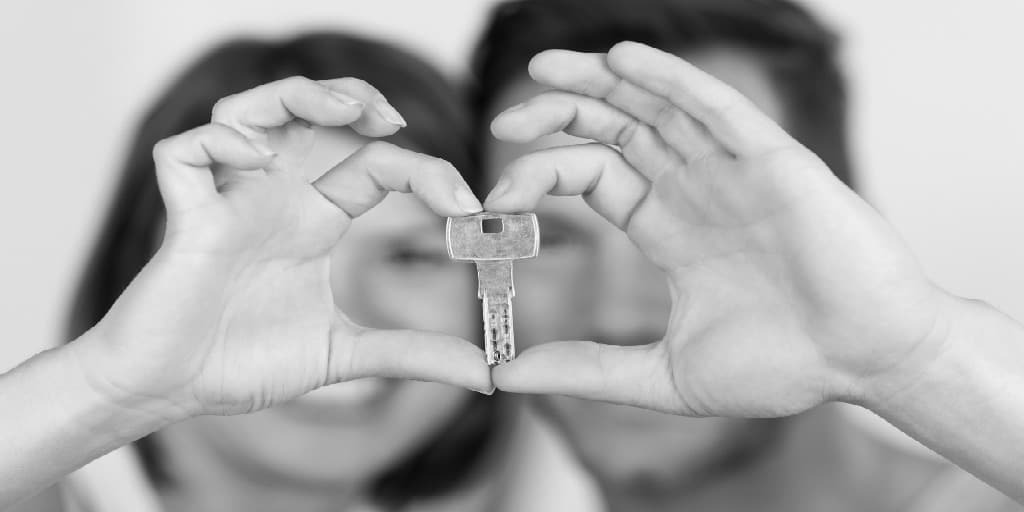 blurred image of couple jointly holding a house key in front of their faces