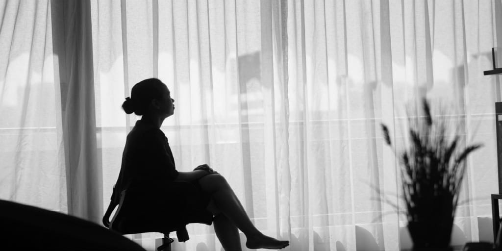 silhouette of women sitting in office chair looking out big window