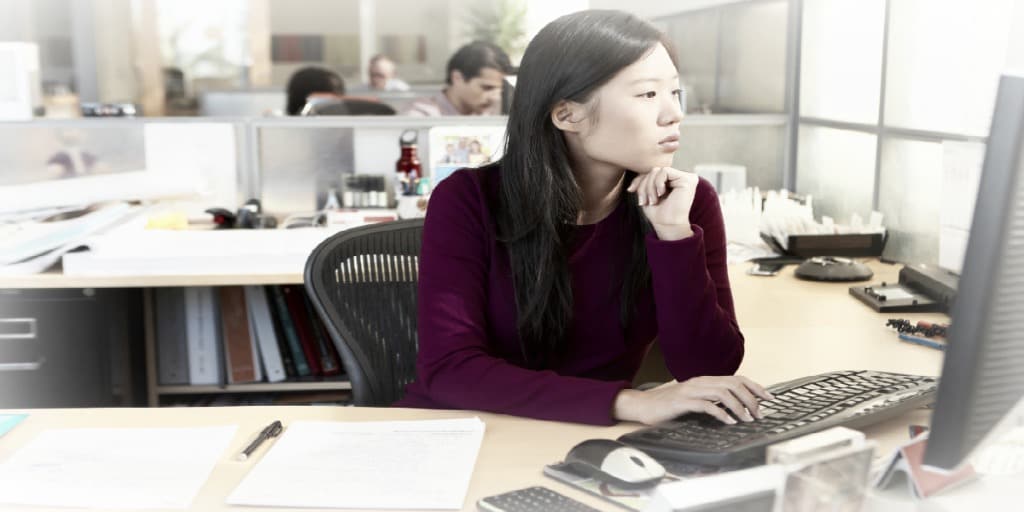 woman working on a computer at her desk in a large office