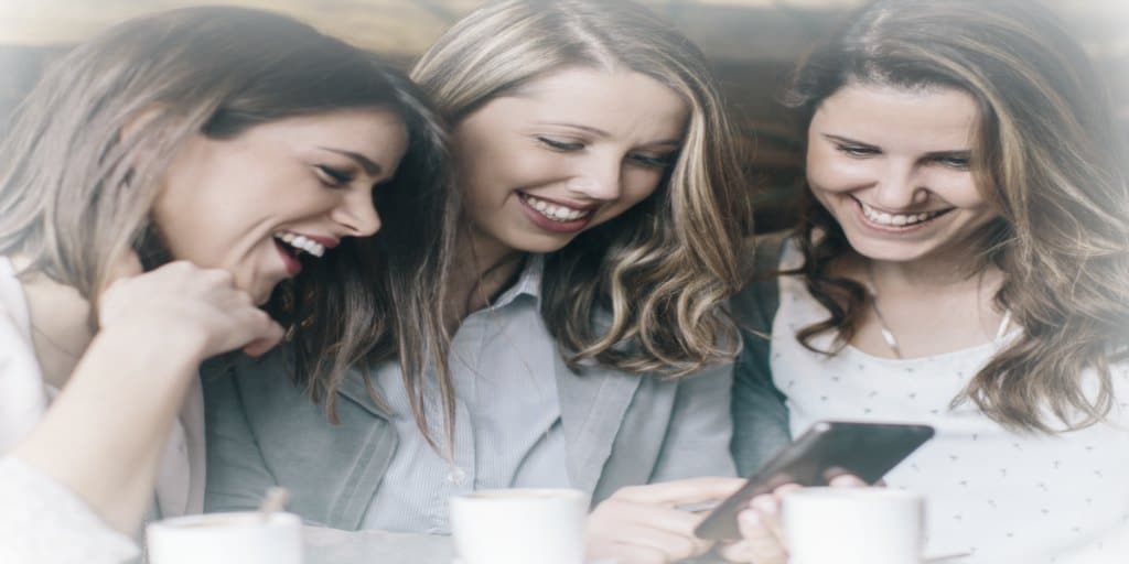 3 young women looking at a cell phone