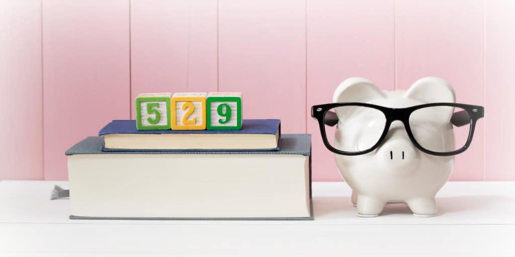 the numbers 529 in wooden blocks on top of stacked books next to white piggy bank