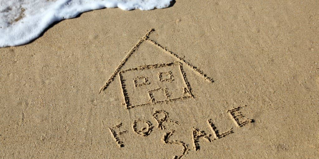 house for sale written in sand at the beach