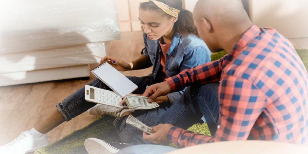 couple reviewing their budget with notepad calculator and money