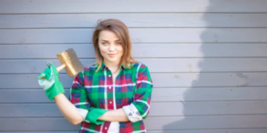 female prepping her home for spring by painting the exterior