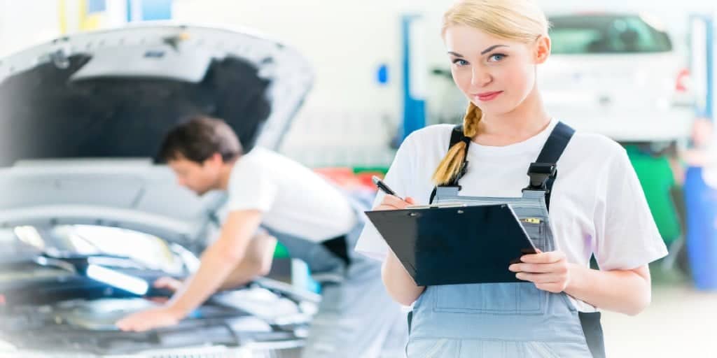 female service writer and male technician performing maintenance on a car