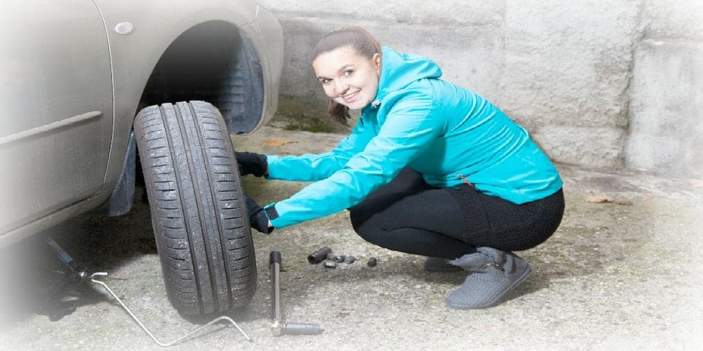 female changing a tire on a car