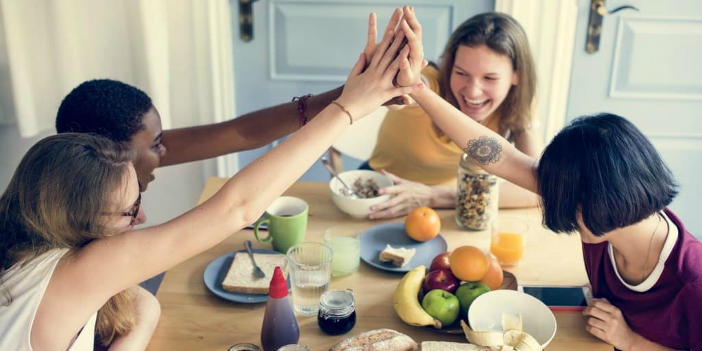 group of four female roommates eating and laughing