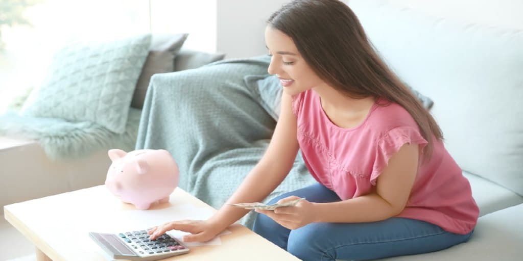 young female using calculator to determine investing strategy, lump sum or dollar cost averaging