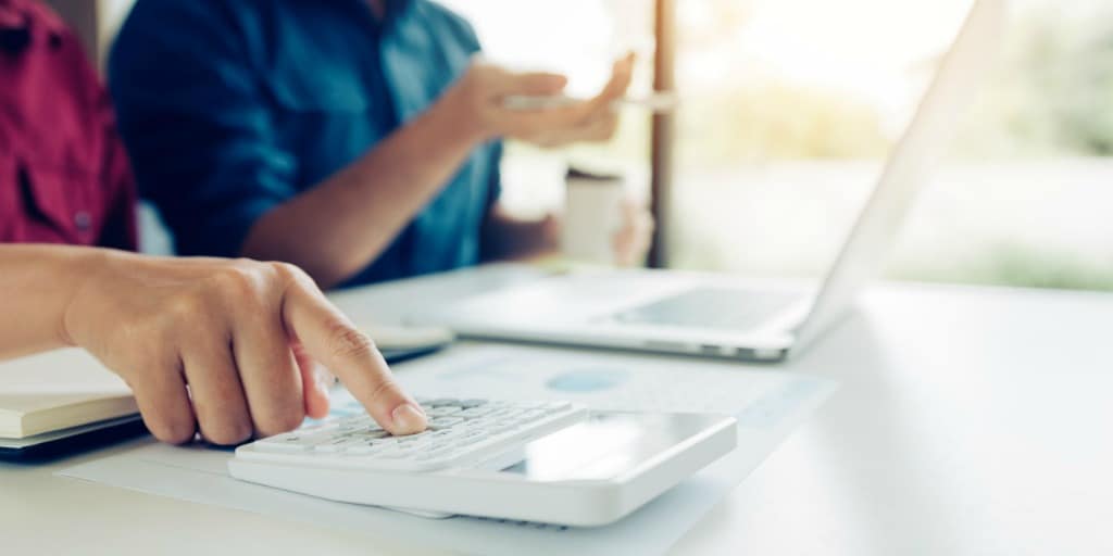 a couple working on their shared living expenses with a calculator and a laptop