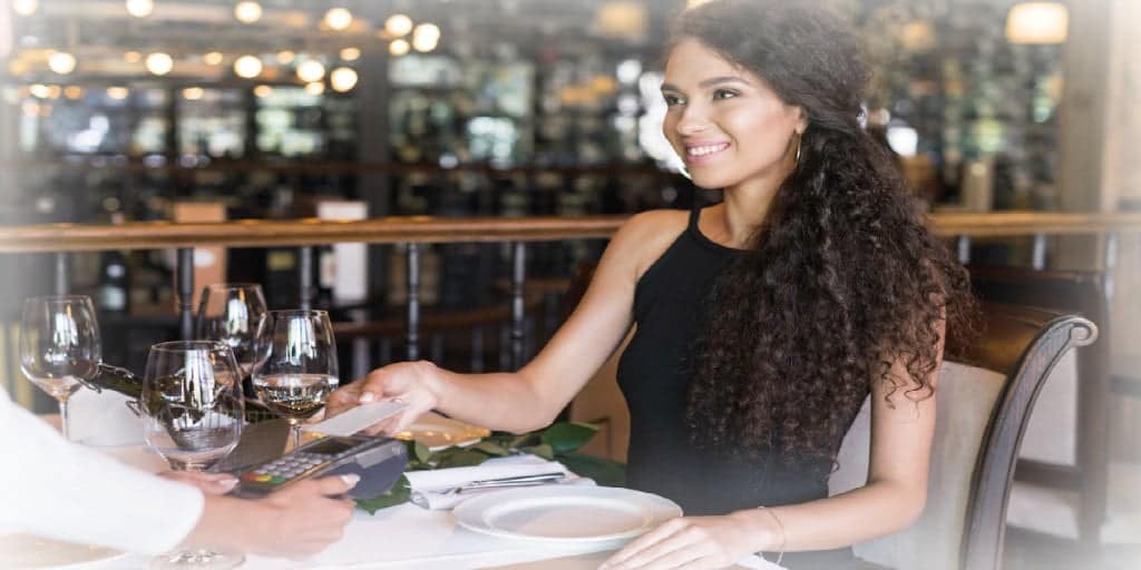 young woman tipping a restaurant  server to express gratitude for service 