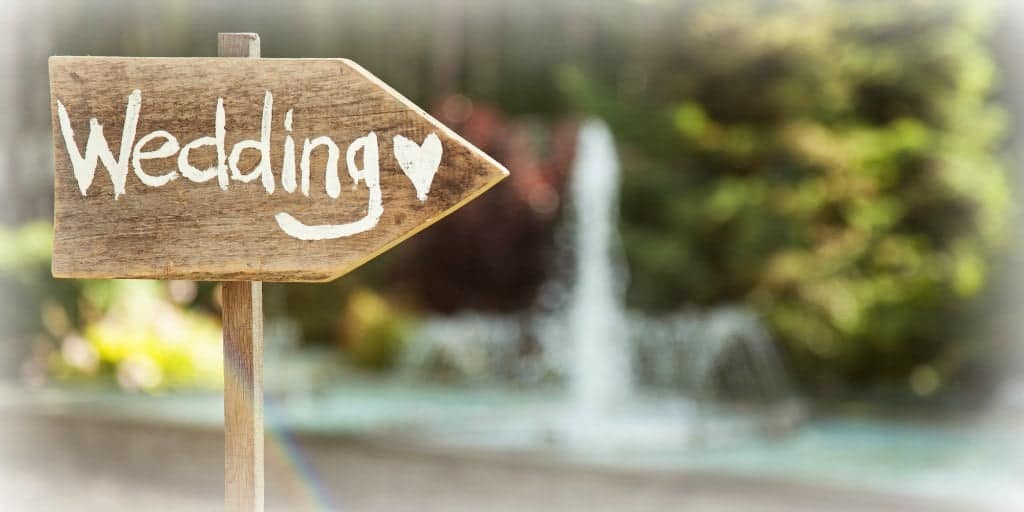 wooden arrow with the word wedding pointing the direction for guests attending a wedding