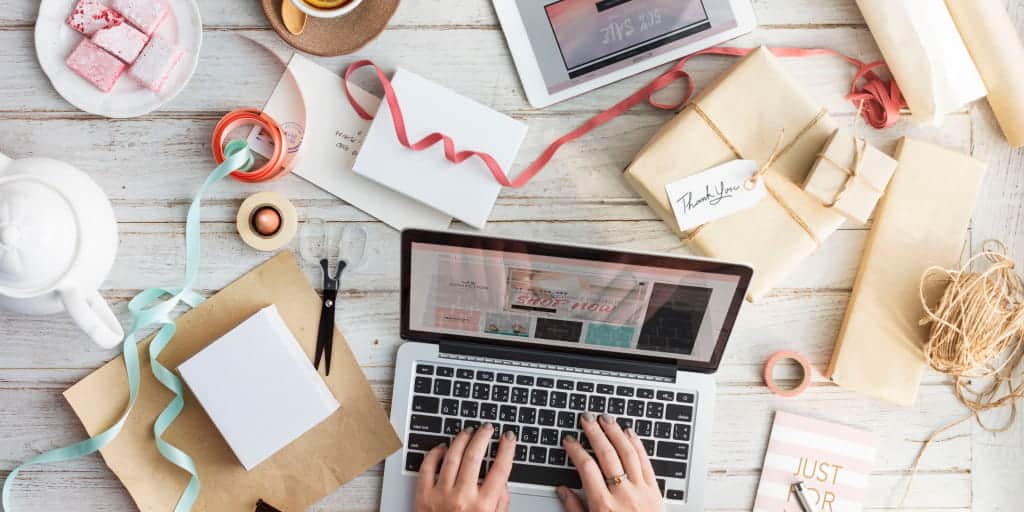 top of desk strewn with a laptop and office gifts and supplies