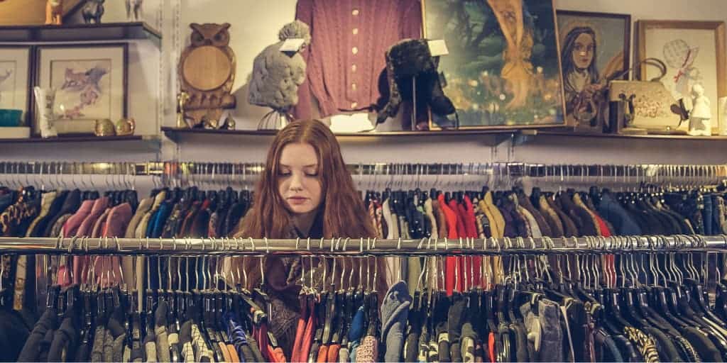 woman looking through clothing in a second hand store