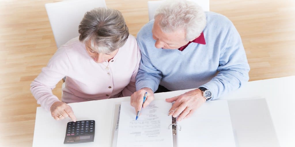 older couple looking over their finances in a binder and using a calculator