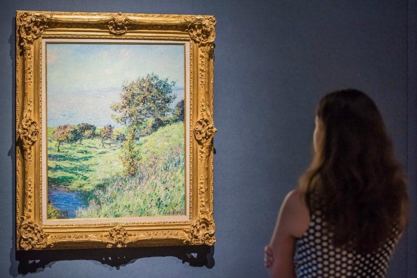 young woman viewing hanging oil painting