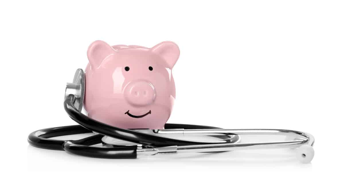 Pink piggy bank and stethoscope on white background