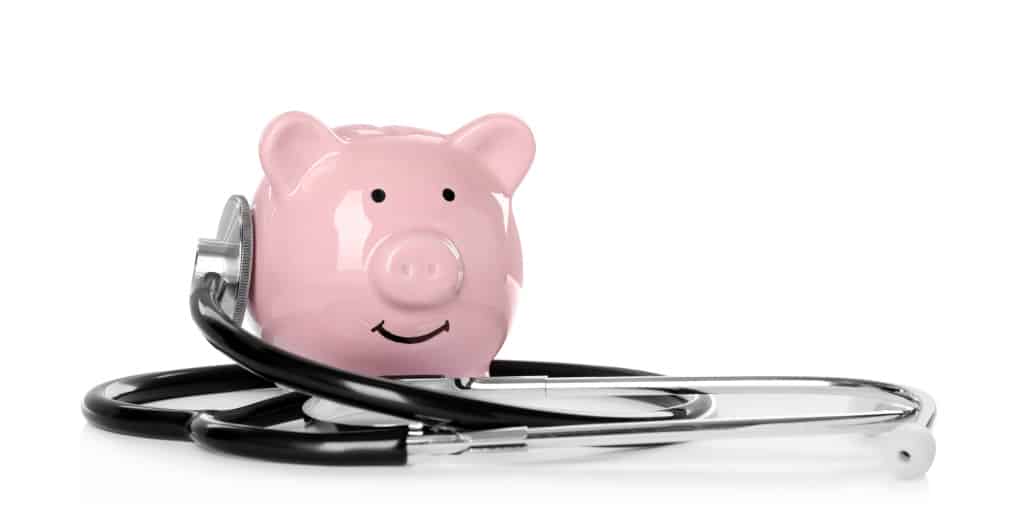 Pink piggy bank and stethoscope on white background