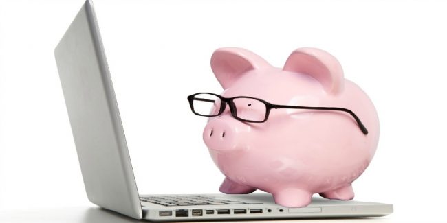 pink piggy bank with glasses sitting on laptop computer depicting a new investor