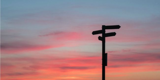 directional sign silhouette agains gorgeous sunset