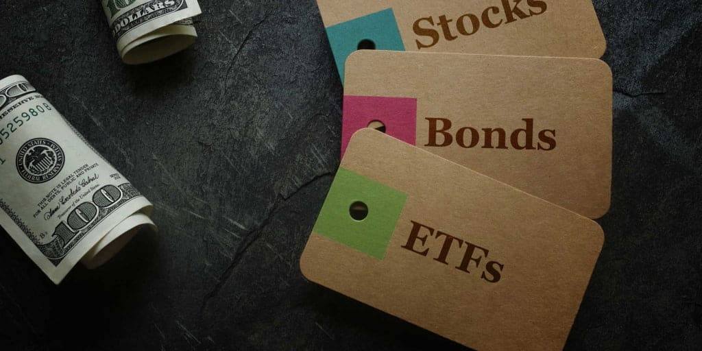 etf bonds and stock tags on table with rolls of money