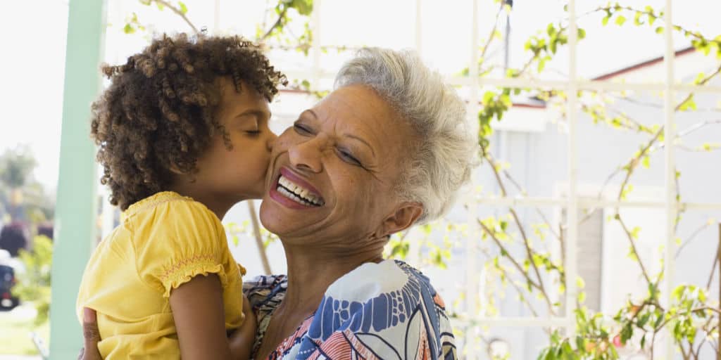 grandchild giving grandmother a kiss on cheek