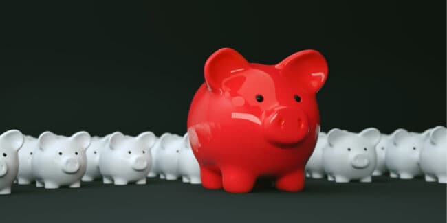 red piggy bank in front of many white piggy banks symbolizing an accredited investor