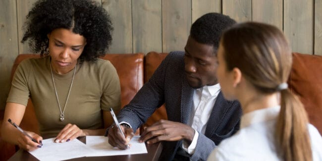 black couple signing a purchase offer for a house