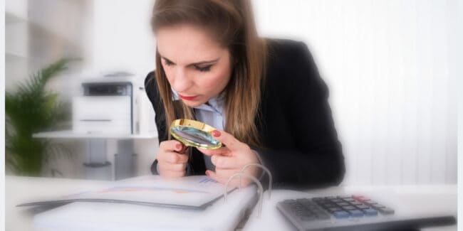 woman reviewing financial tax documents with a magnifying glass