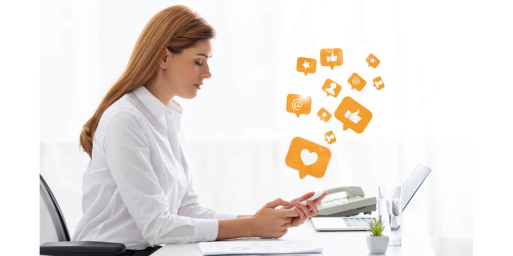 female social media manager on smartphone at her desk