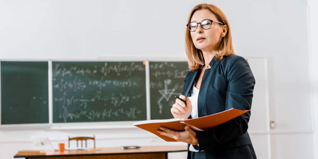 female teacher in classroom reviewing a plan
