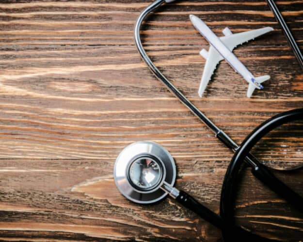 model airplane and stethoscope on wood background symbolizing travel and healthcare concept