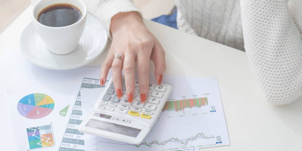 woman using a calculator and financial documents to create a financial plan