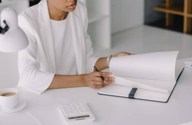 woman preparing to do financial planning in an office with calculator and notebook while drinking coffee