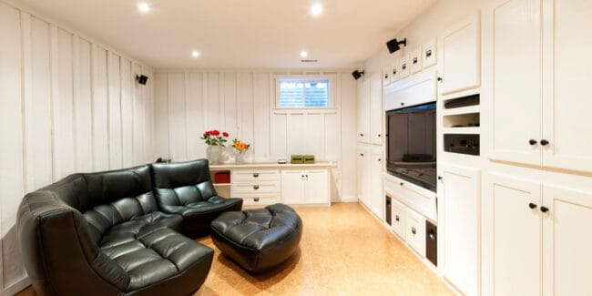 Finished basement of residential home with entertainment center, couch and flat screen television.