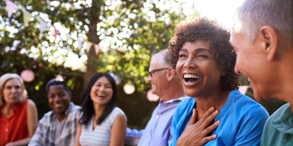 middle aged friends talking and laughing in backyard