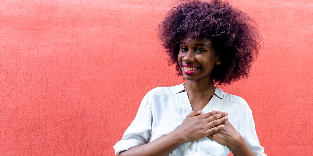 African American woman makes a gesture of gratitude with hands over heart as a concept of self love and financial health