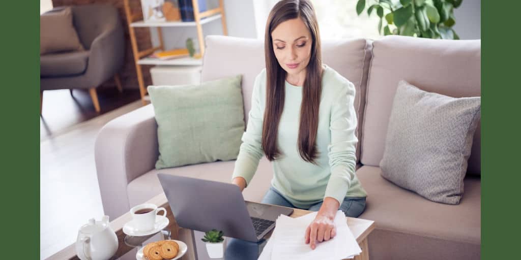 dark haired woman sitting in living room with her laptop working on her finances