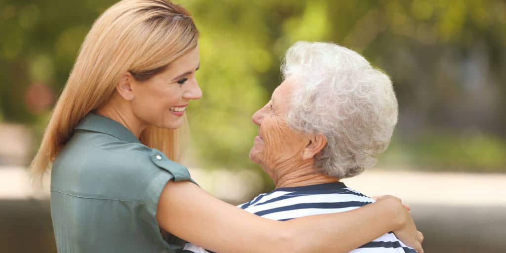 younger woman embracing and gazing lovingly at elderly woman