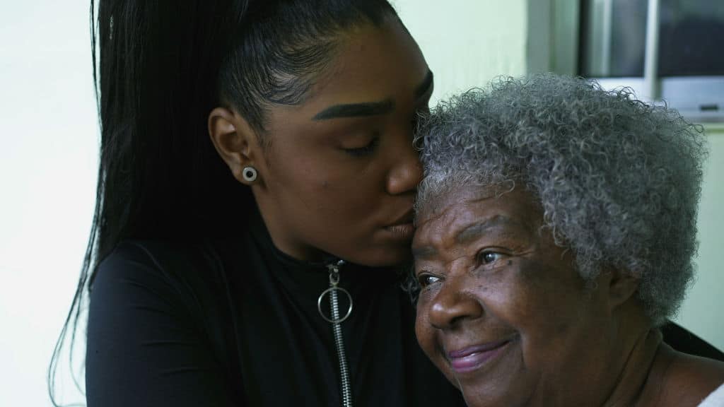 portrait of the faces of a grandmother and granddaughter posing in loving embrace for camera together