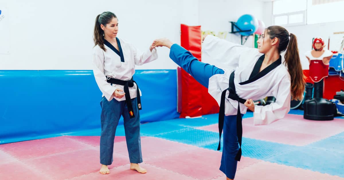 Two young women practice taekwondo in a training center