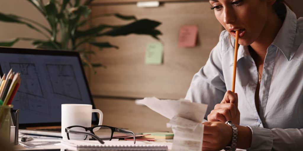 Mujer pensativa que trabaja en sus finanzas y calcula las facturas con el escritorio