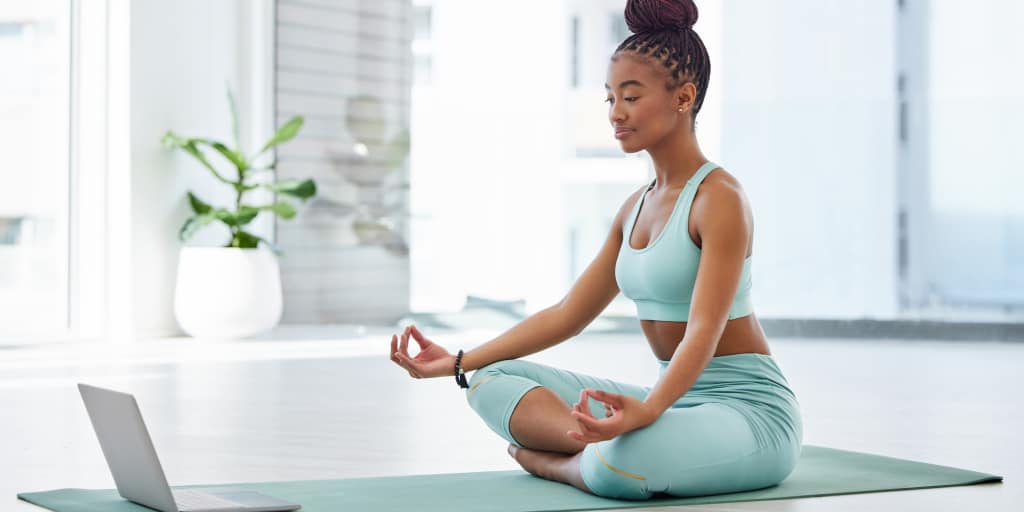 young african american woman practicing a sitting yoga pose on a mat