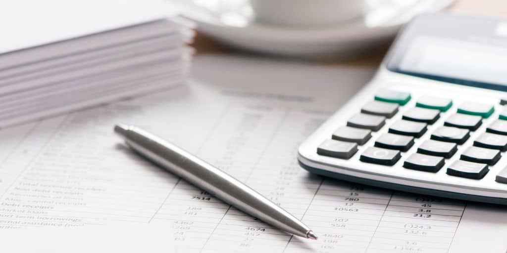 calculator and pen with financial documents on a desk top