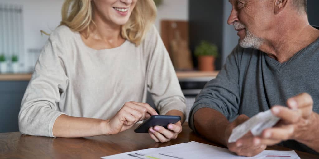 caucasian woman using calculator to help senior relative make money decisions