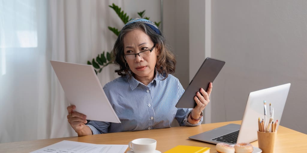 Retrato de una anciana que trabaja dentro de la casa usando computadoras portátiles y tabletas para trabajar y verificar documentos financieros importantes 